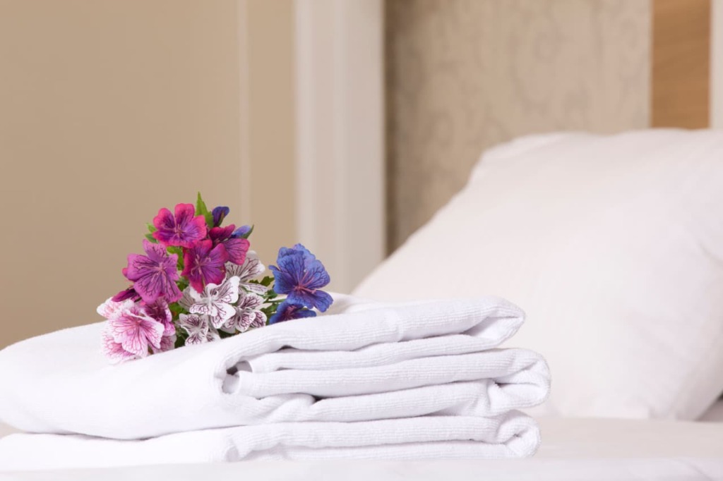 Welcome floral arrangement with fresh towels on a hotel bed